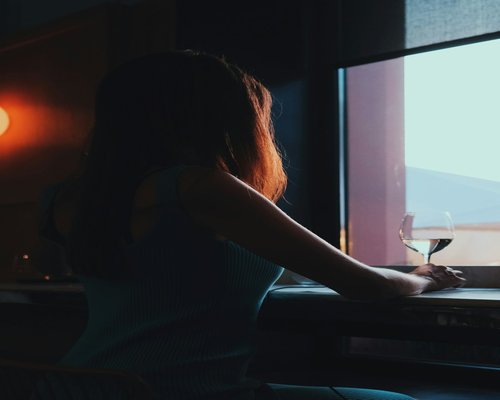 Woman drinking water and looking out the window away from computer